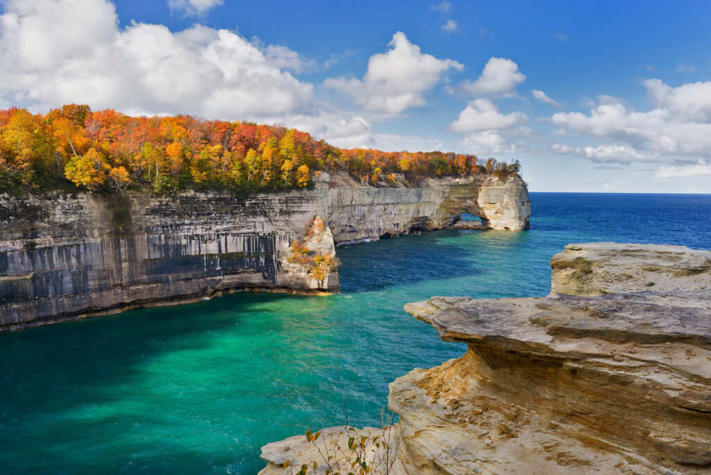 rock cliffs, green-blueish water with fall-colored tress on 